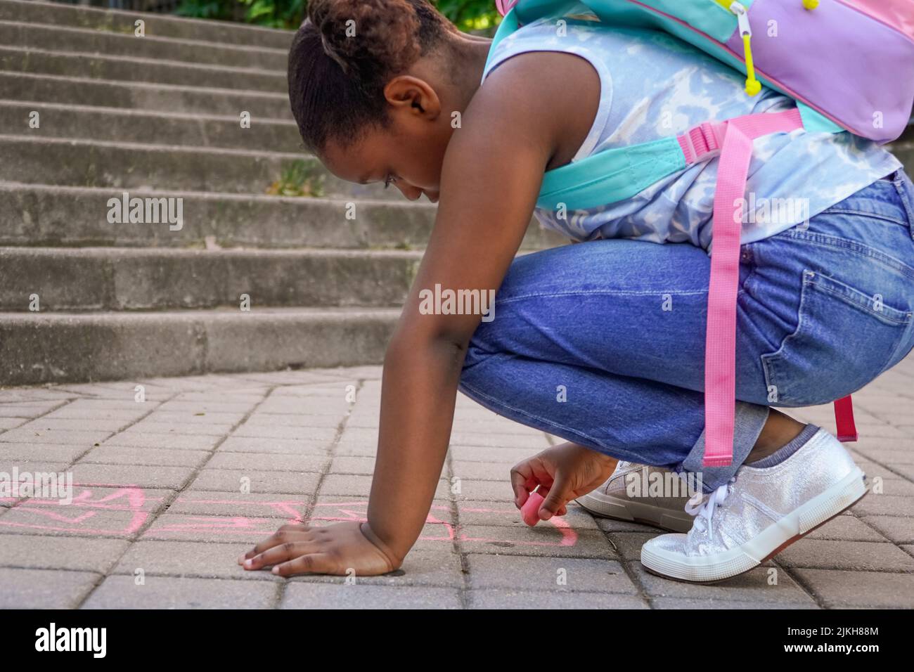 fille dessin avec craie sur le sol de l'aire de jeux de l'école. Concept de retour à l'école. Groupe multiethnique d'enfants Banque D'Images