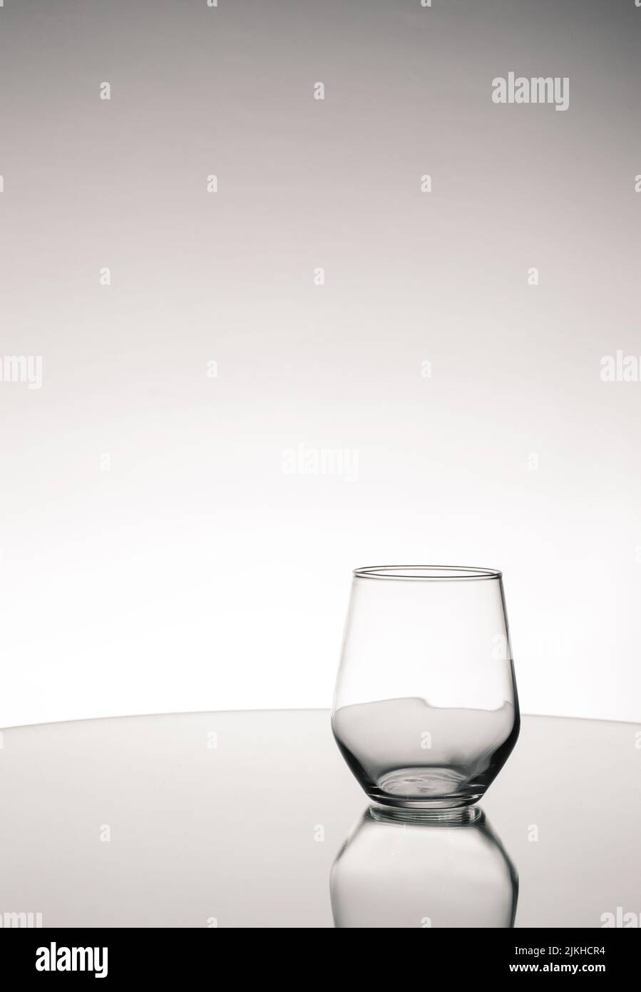Prise de vue en niveaux de gris d'une coupelle en verre vide avec réflexion sur une surface miroir Banque D'Images
