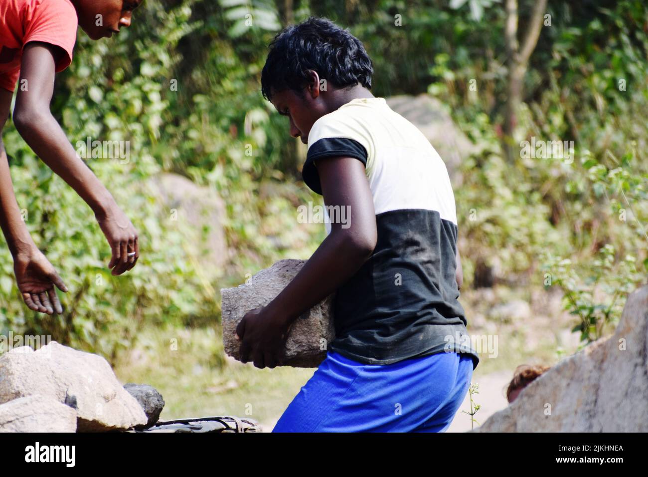 Un gros plan d'un enfant tenant une pierre lourde dans l'extraction de pierre et de charbon à Dhanbad Banque D'Images