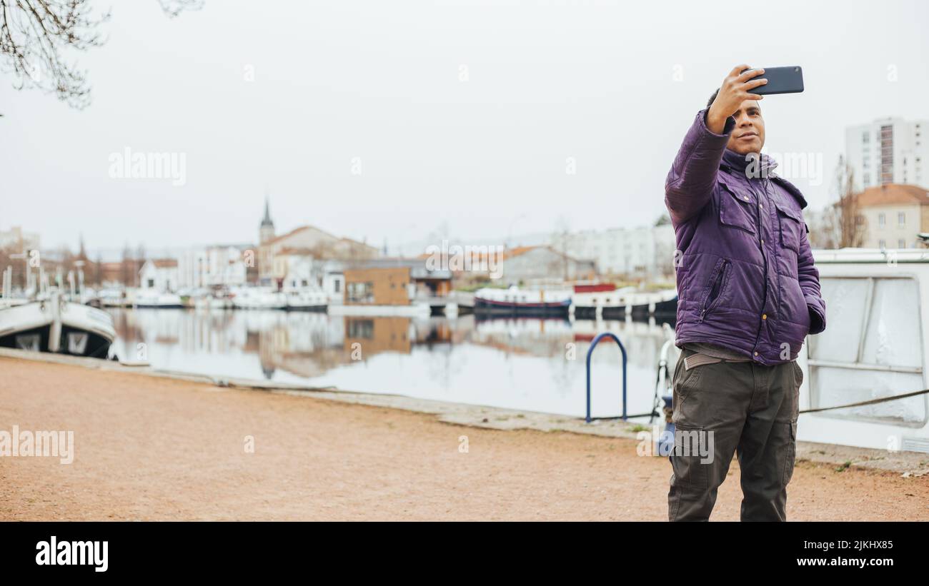 Beau latin homme dans le port prenant des photos avec son mobile Banque D'Images