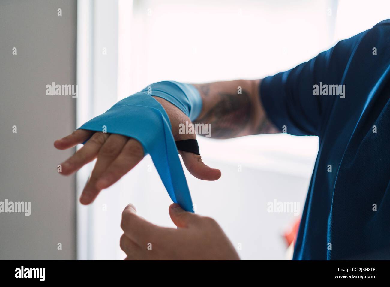 Un homme mettant des élastiques bleus sur sa main, se préparant à faire du sport Banque D'Images