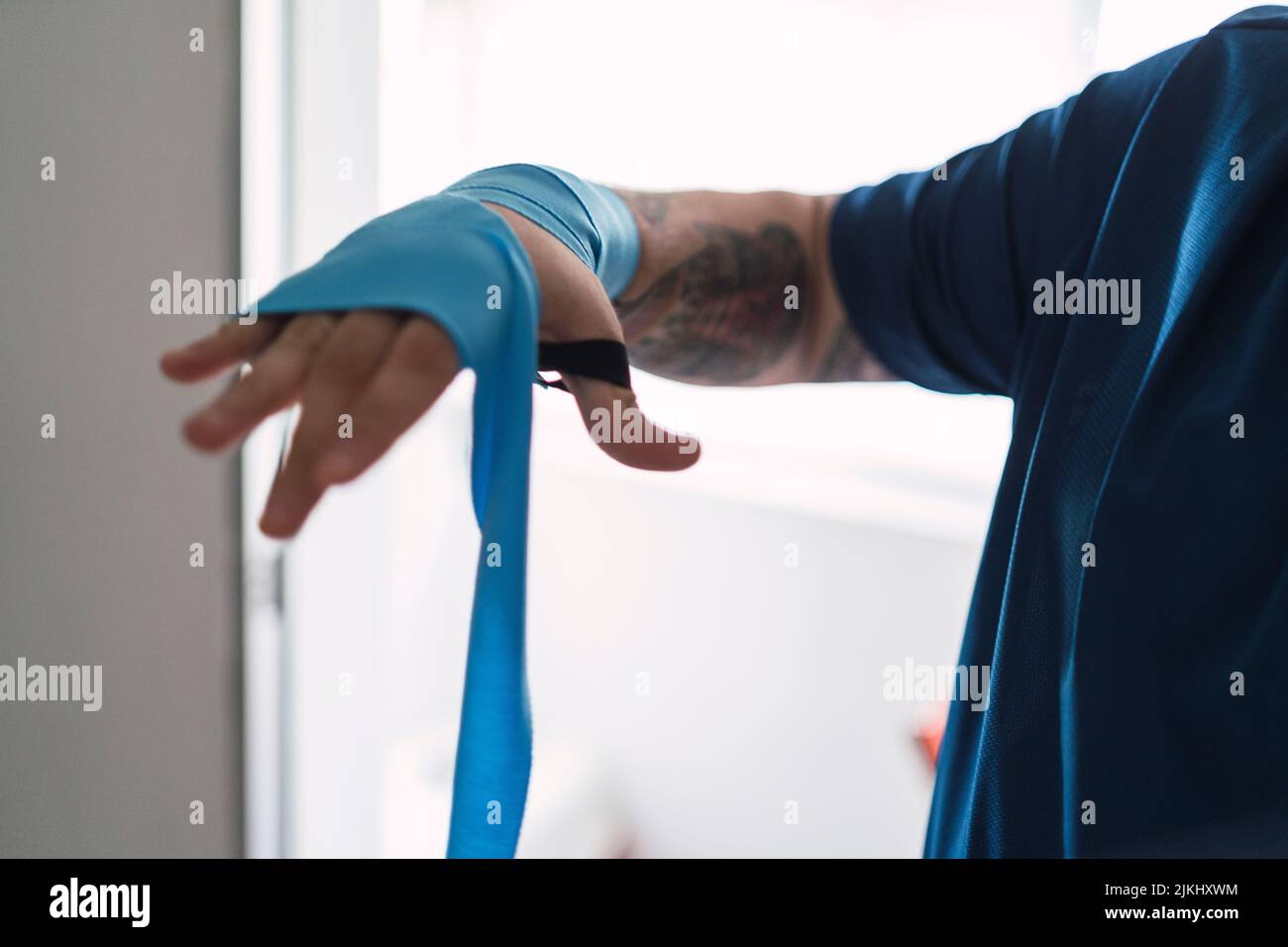 Un homme mettant des élastiques bleus sur sa main, se préparant à faire du sport Banque D'Images