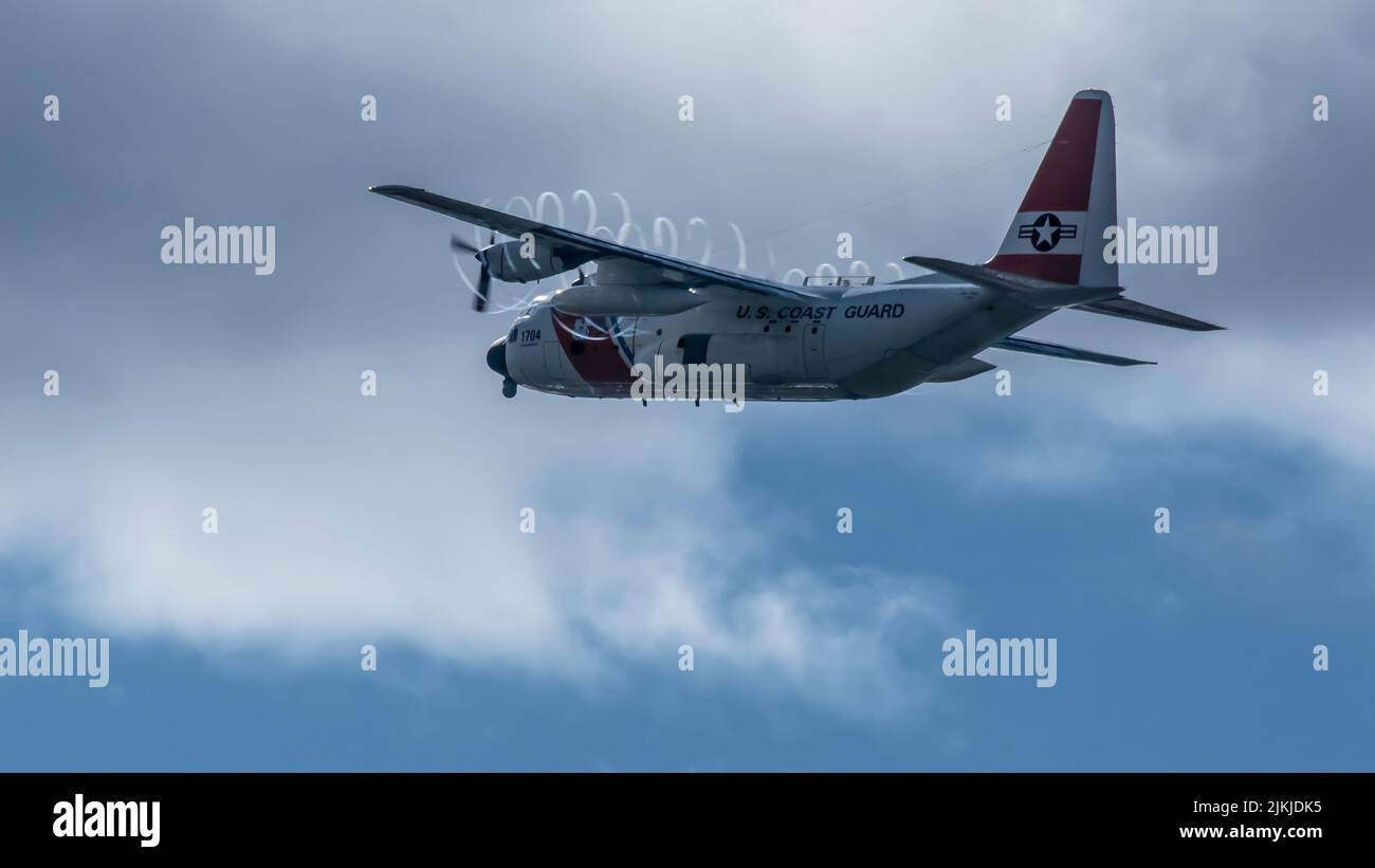 Un gros plan d'un avion de la Garde côtière américaine volant dans un ciel nuageux et clair Banque D'Images