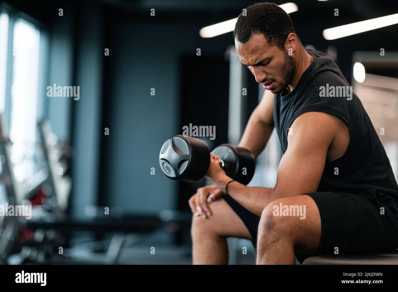 Jeune athlète masculin noir entraînement avec Dumbbell, faisant des biceps assis Curl Banque D'Images