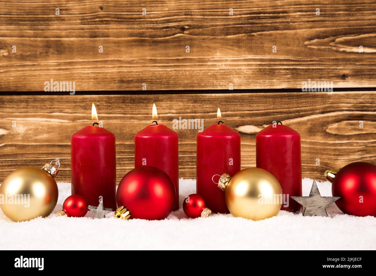 Bougies rouges avec boules de Noël sur fond de bois sur neige Banque D'Images