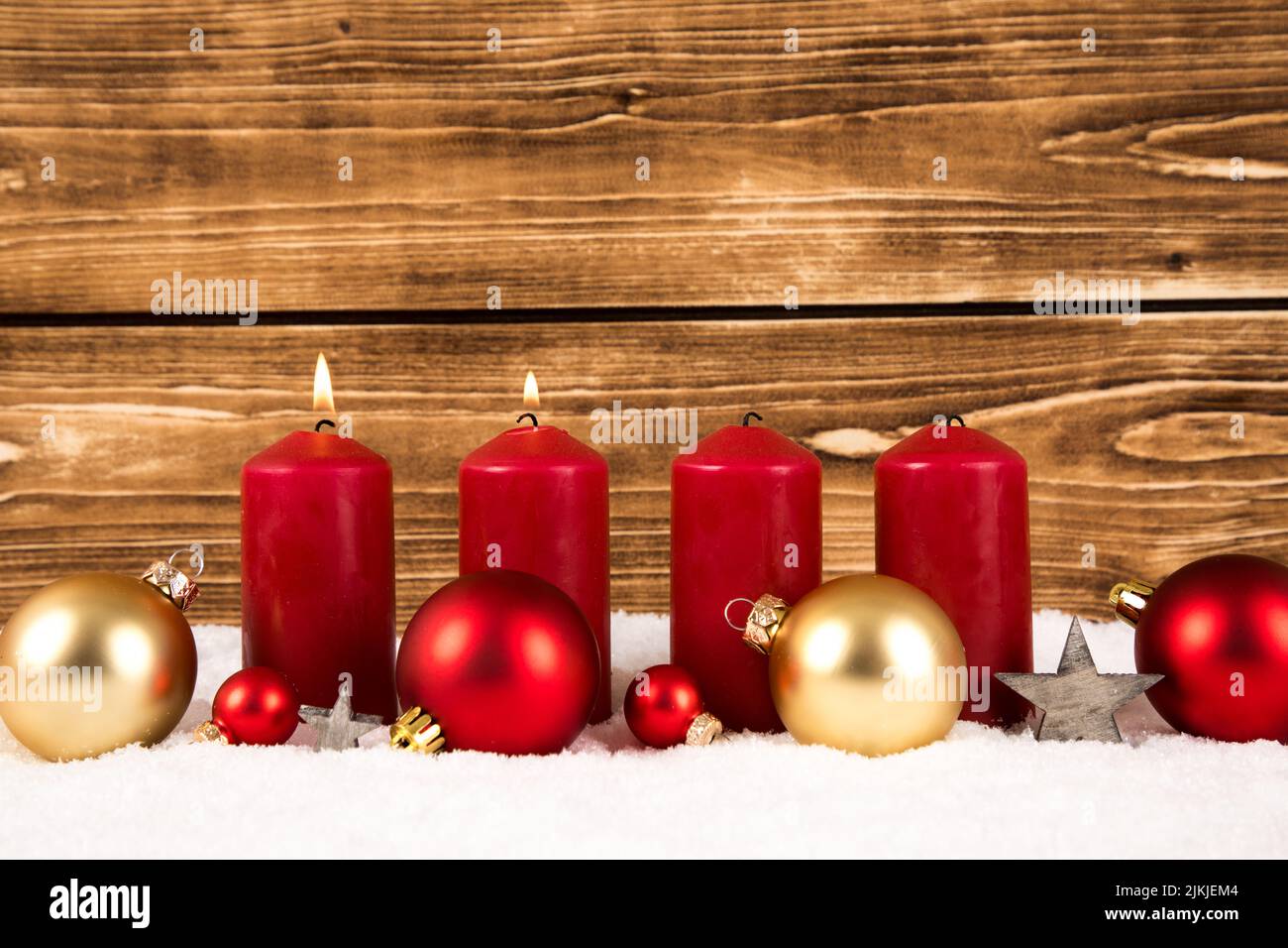 Bougies rouges avec boules de Noël sur fond de bois sur neige Banque D'Images
