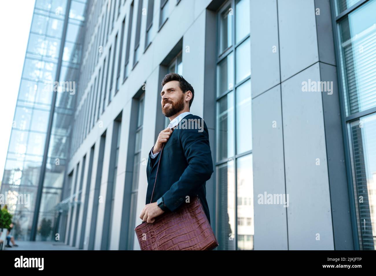 Joyeux homme d'affaires européen du millénaire avec une barbe en costume et un sac pour un espace libre Banque D'Images