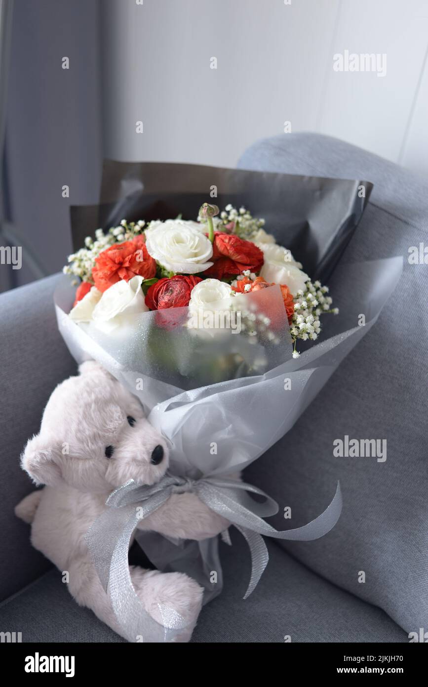 Un adorable ours en peluche et un bouquet de fleurs Banque D'Images