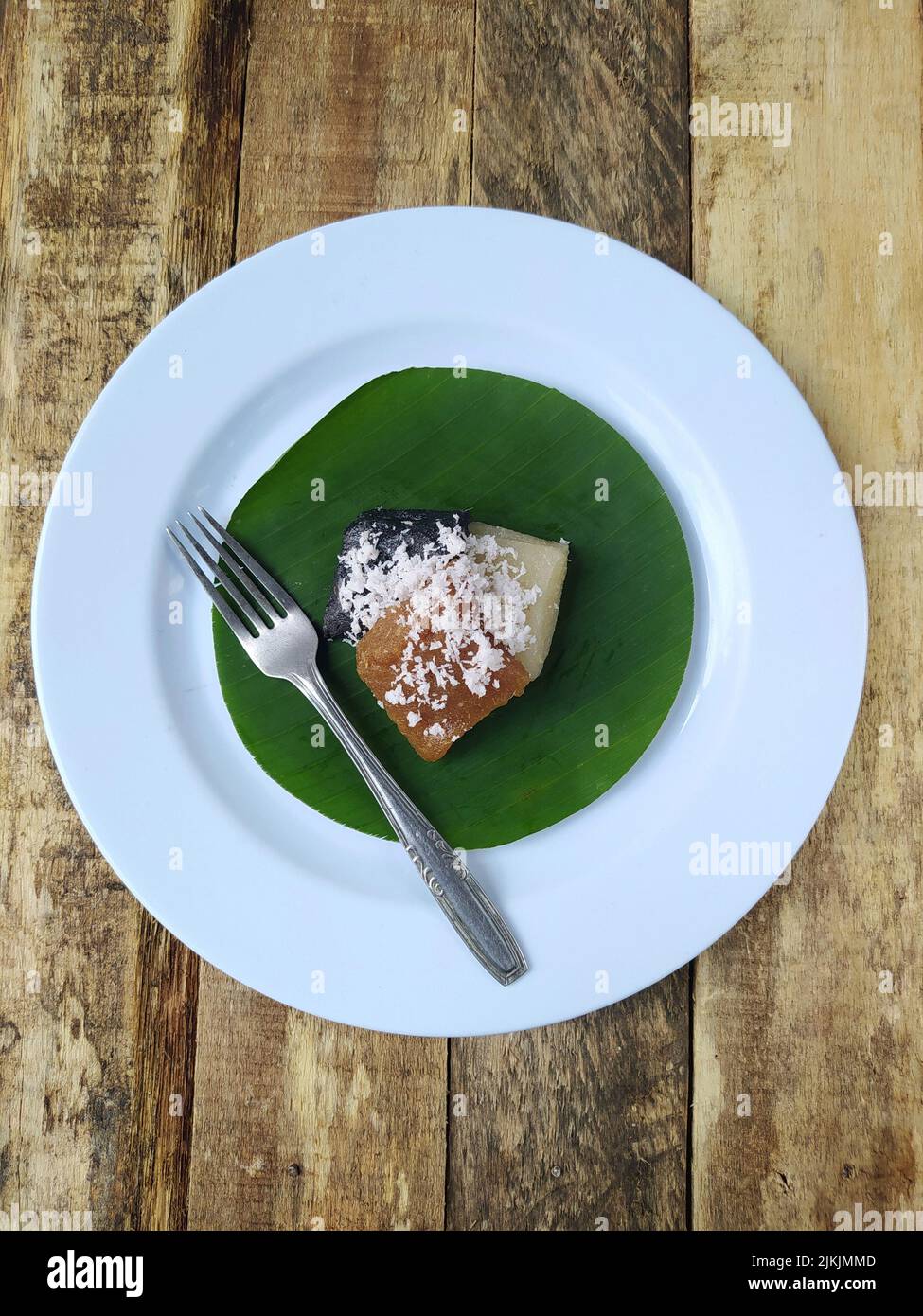 Vue de dessus getuk ou de la nourriture de manioc et de noix de coco sur une assiette et feuille de banane avec table en bois, la nourriture traditionnelle de Java indonésien Banque D'Images