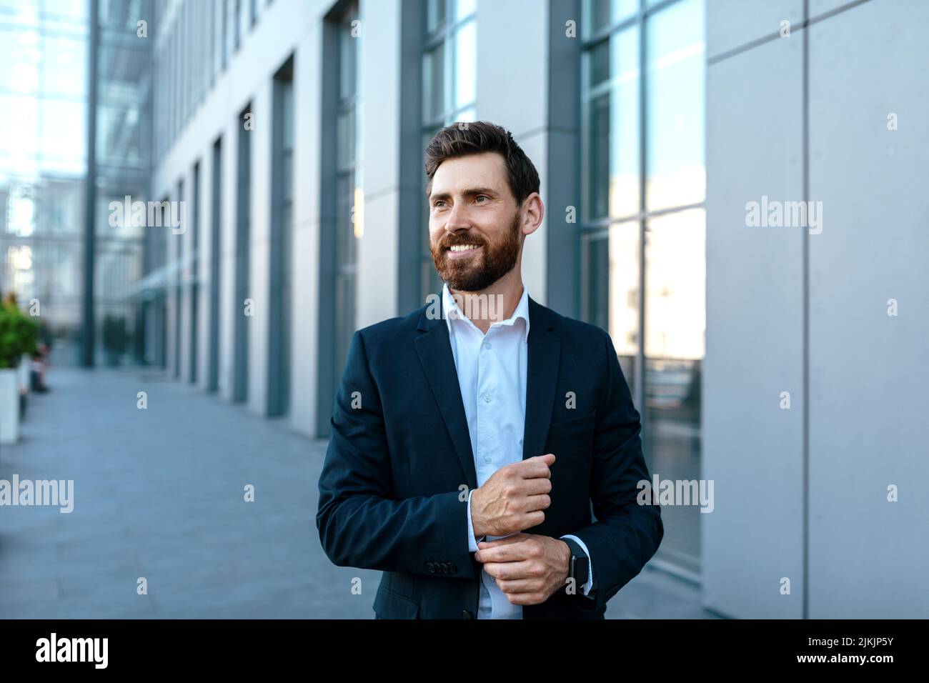 Souriant et confiant, le jeune homme d'affaires caucasien avec sa barbe en costume a une vue sur l'espace libre Banque D'Images