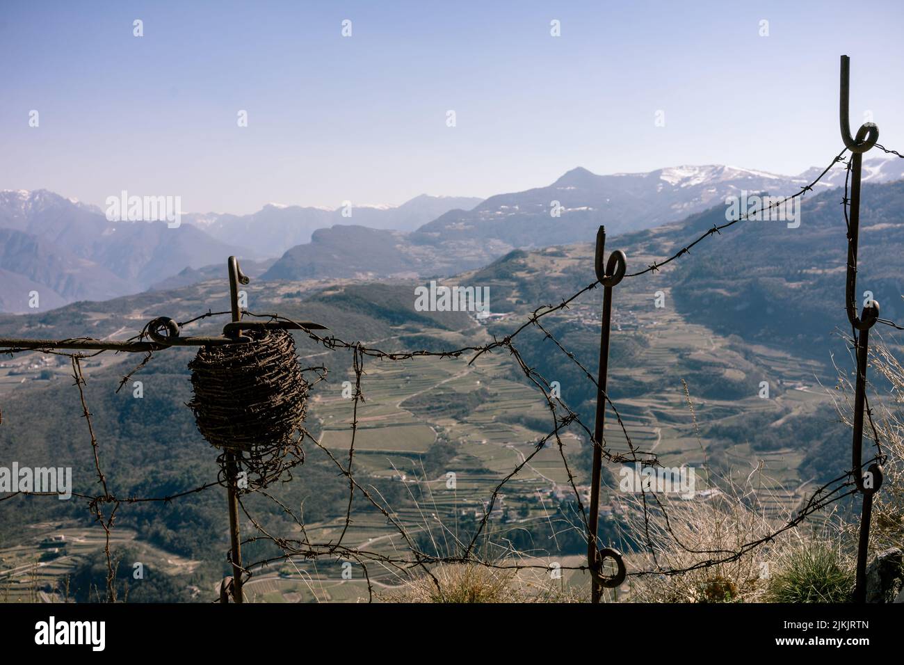 Un gros plan d'un rouleau de barbelés vintage accroché à un vieux poteaux d'escrime. Montagnes en arrière-plan Banque D'Images