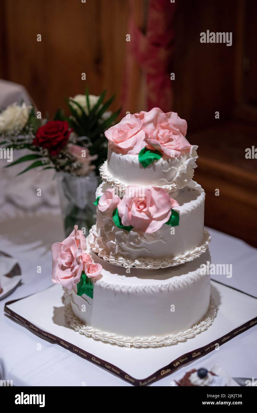 Un gros plan vertical du gâteau de mariage blanc traditionnel de trois étages avec roses roses roses Banque D'Images