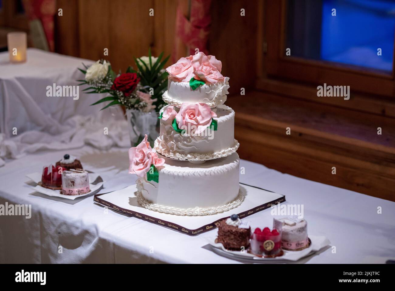 Un gros plan du gâteau de mariage blanc traditionnel de trois étages avec roses roses roses Banque D'Images