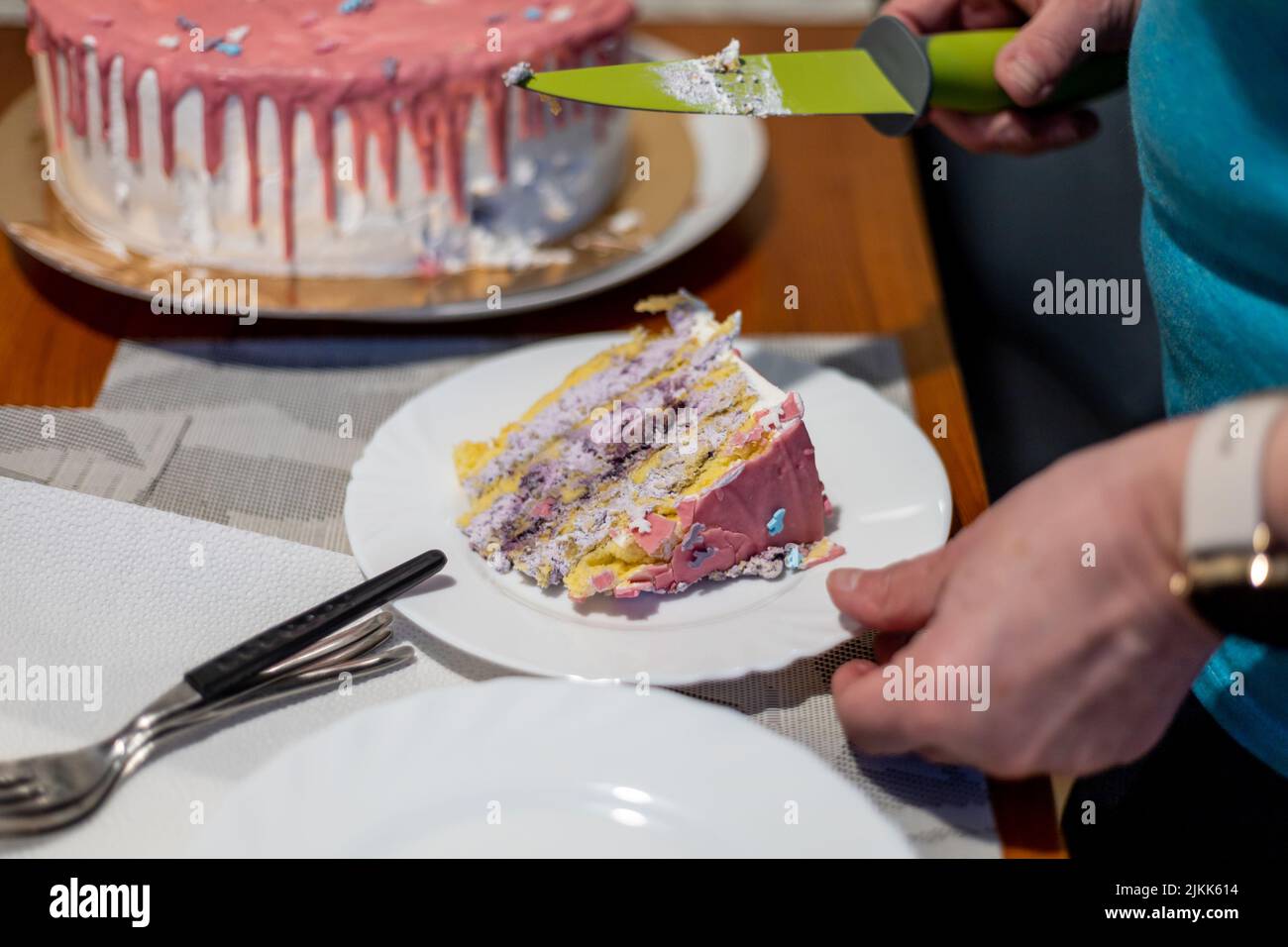 A photo of man's hands holding a piece of a birthday cake slice in a plate and a knife Banque D'Images