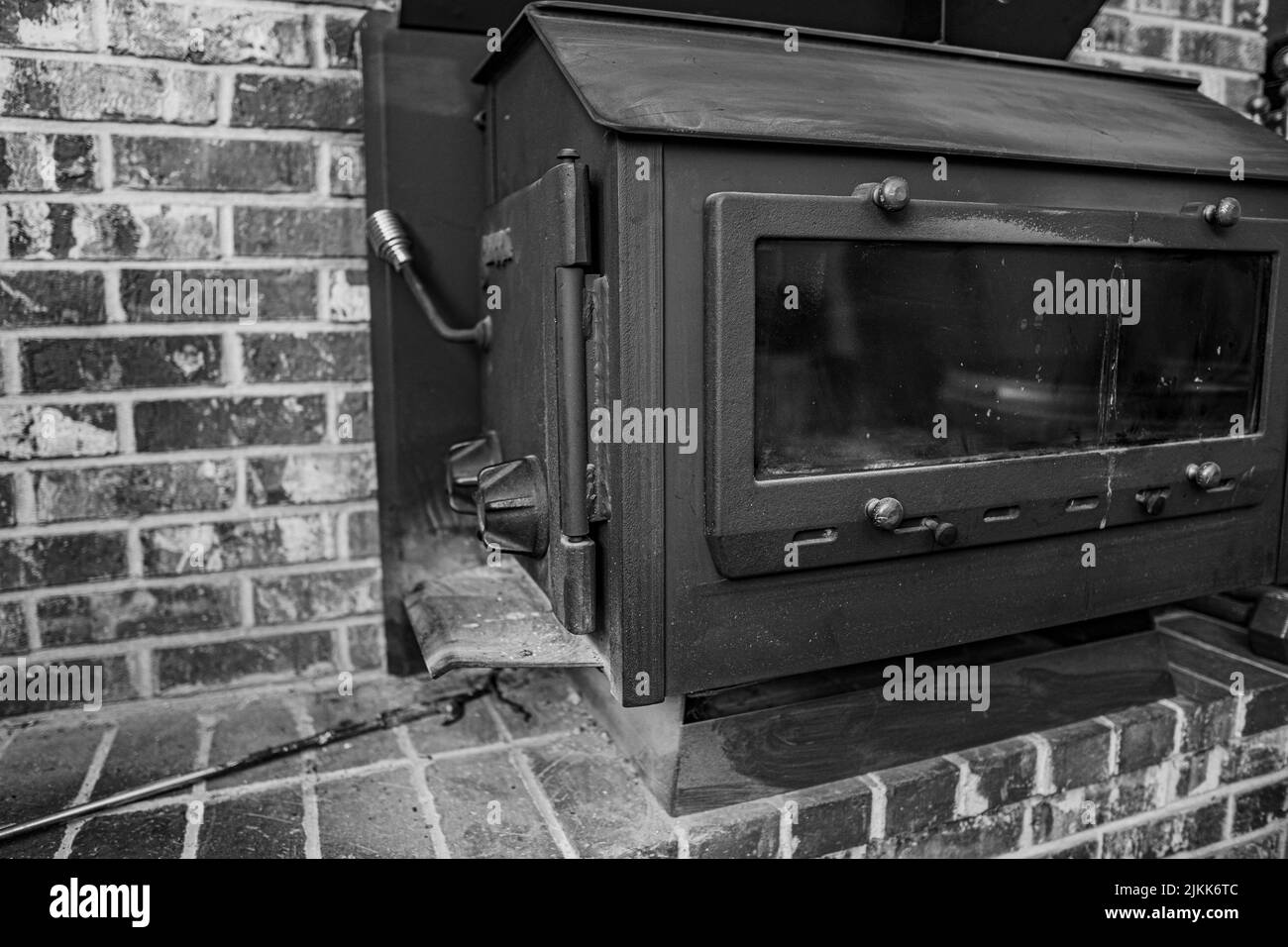 Une photo en niveaux de gris d'un vieux poêle à bois dans une maison en brique Banque D'Images