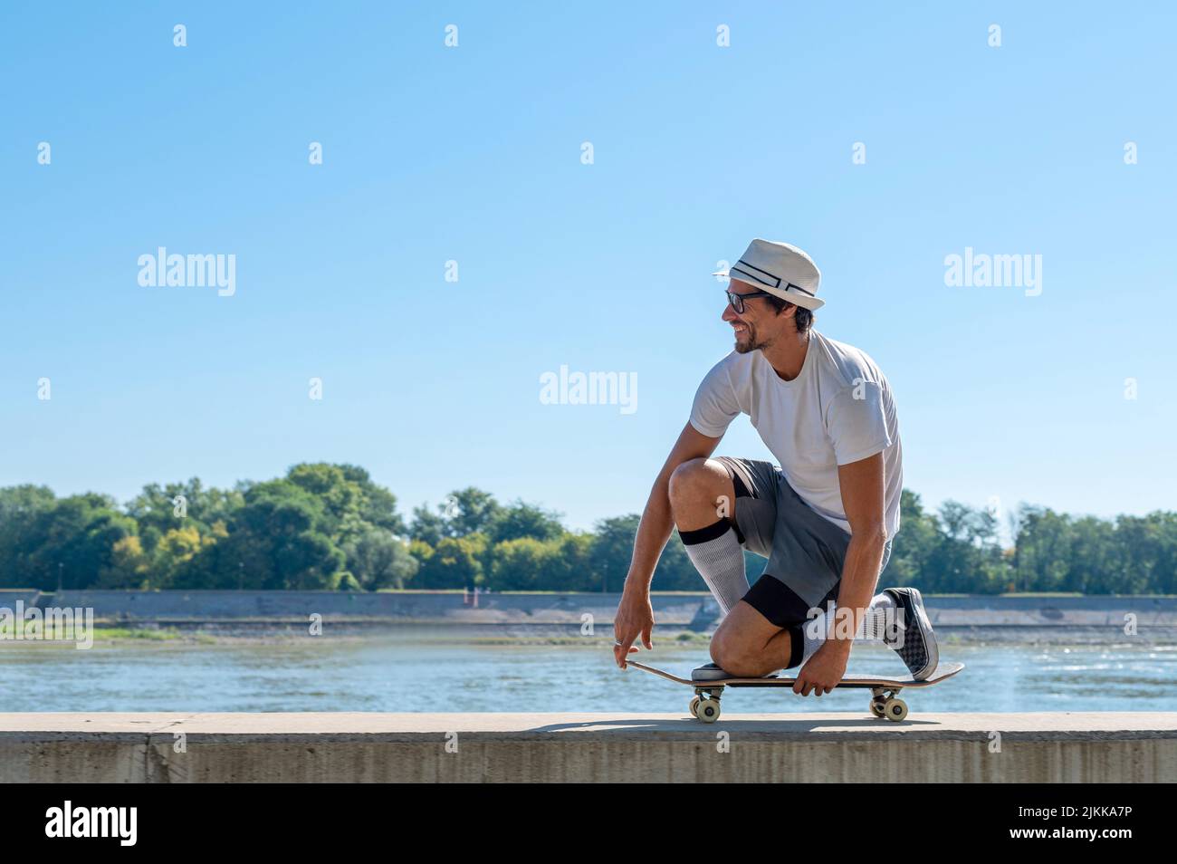 Un skateboarder caucasien conduisant sur une barrière en arrière-plan d'un lac Banque D'Images