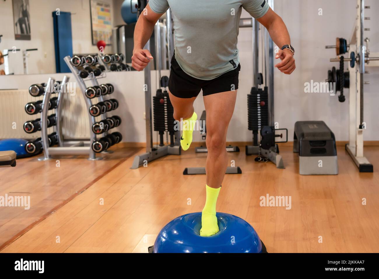 Portrait d'un homme caucasien dans la salle de gym faire des exercices de cheville sur une sphère de caoutchouc, une vie saine et saine faire du sport Banque D'Images