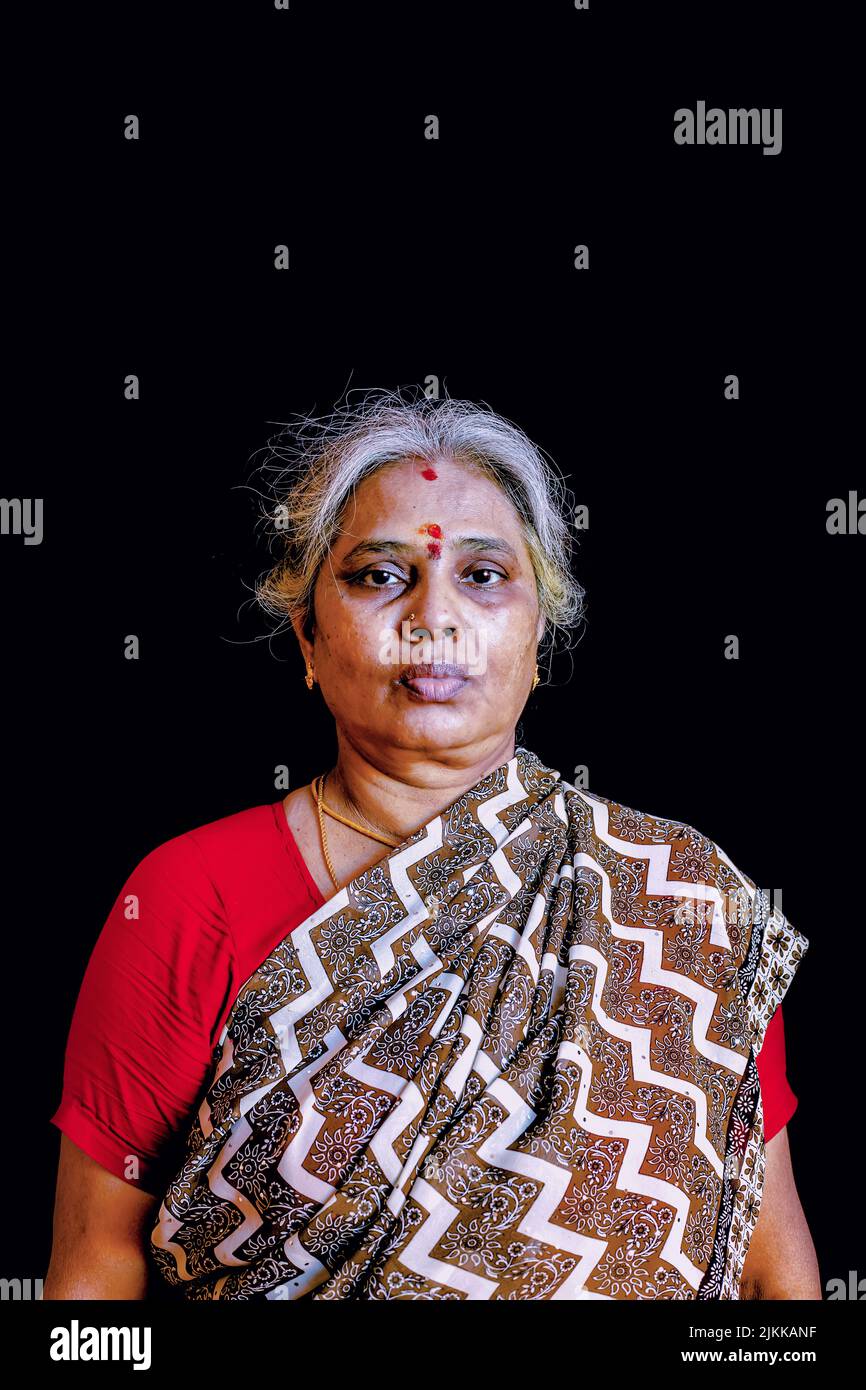 Une photo verticale de femme âgée indienne en robe traditionnelle sari regardant l'appareil photo Banque D'Images