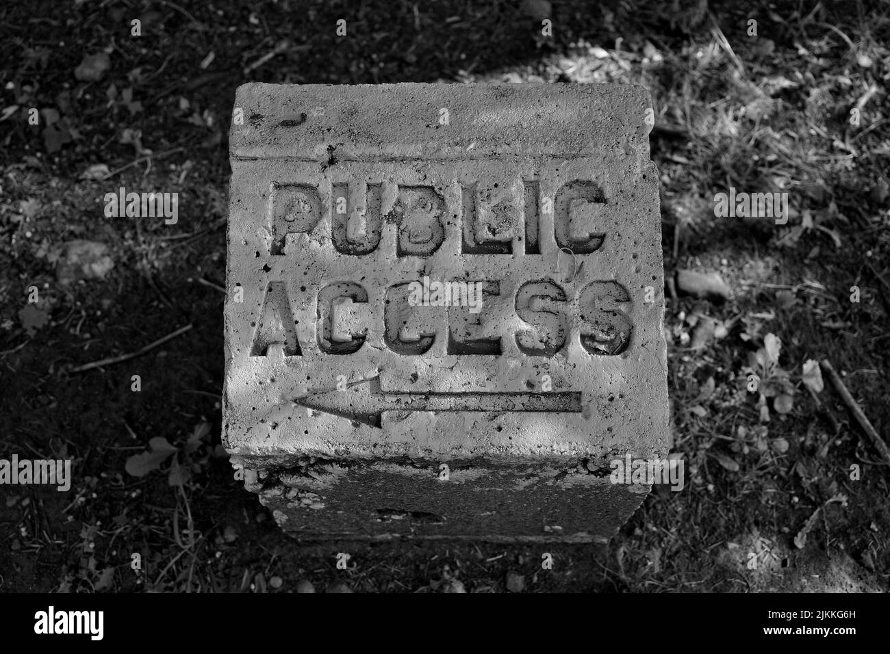 Un gros plan en échelle de gris du panneau public Access avec une flèche vers la gauche sur un poteau en béton Banque D'Images