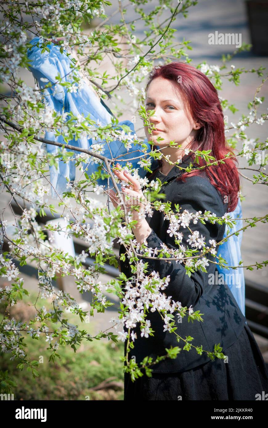 Une photo verticale d'une belle femme caucasienne à tête rouge entourée de petites fleurs Banque D'Images