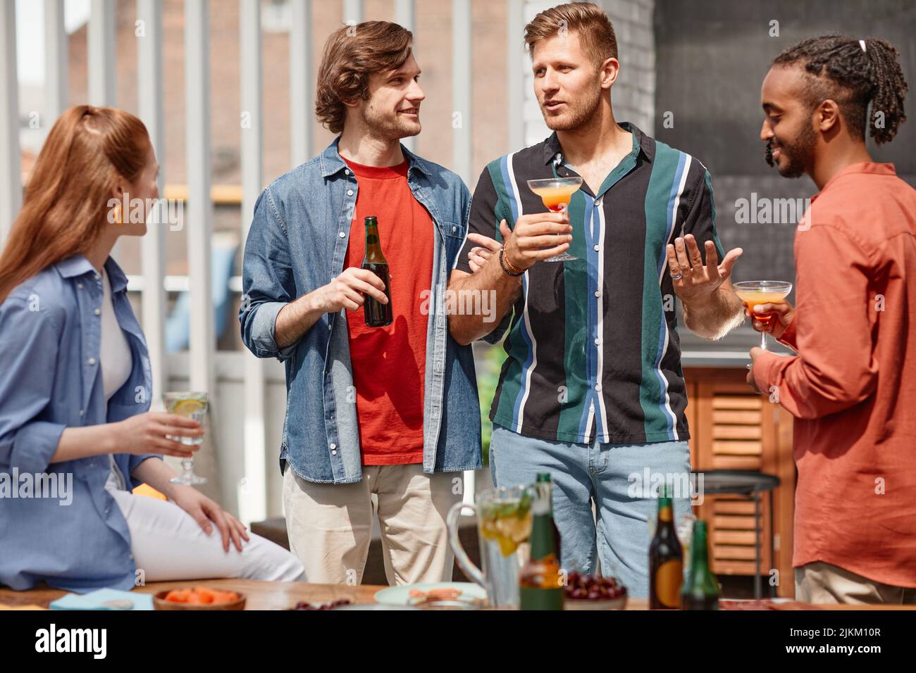 Portrait de deux jeunes hommes accueillant un dîner en plein air avec divers groupes d'amis Banque D'Images