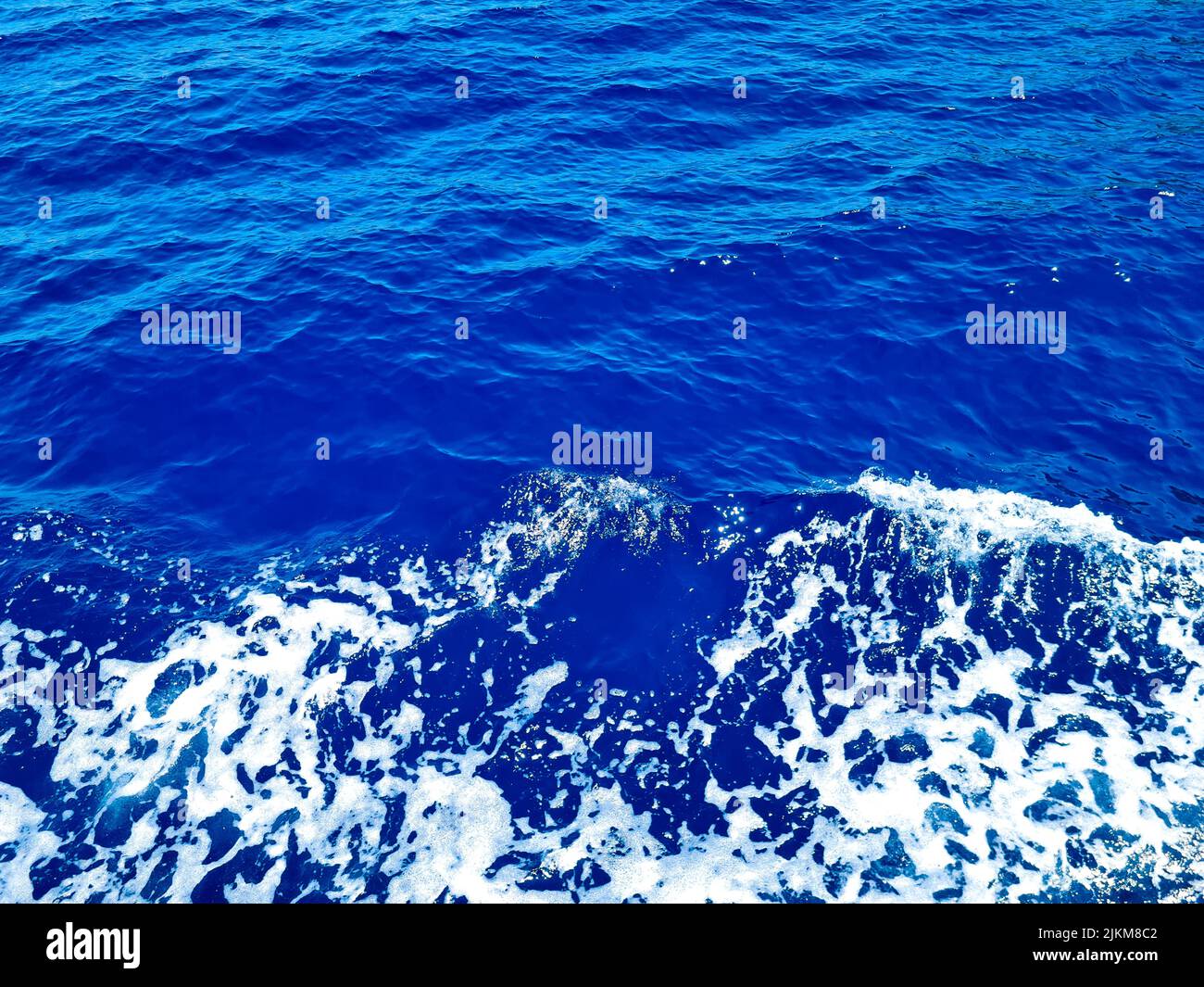 Surface bleu profond d'eau de mer transparente avec des glints solaires Banque D'Images