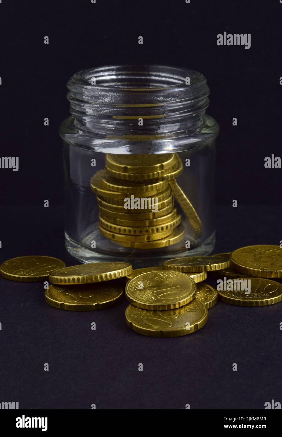 Les pièces en euros sont dispersées et dans le pot de verre isolé sur un fond noir Banque D'Images