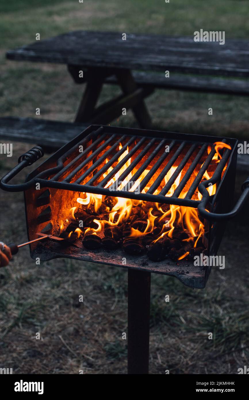 Un cliché vertical d'une flamme brûlante dans un grill extérieur près d'une table de pique-nique. Banque D'Images