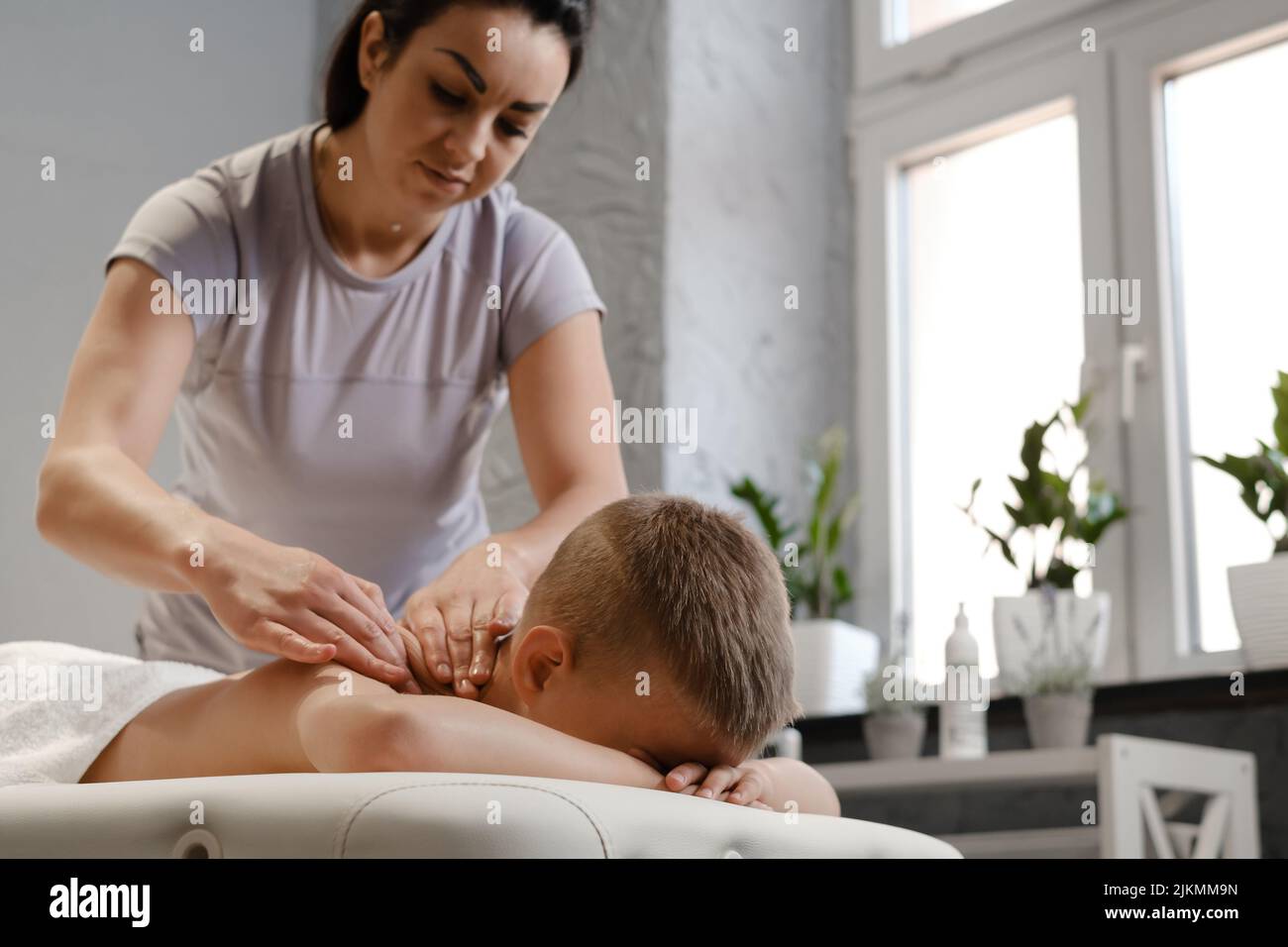 le masseur donne à l'enfant un massage du dos. Concept de massage pour enfants. Massothérapeute offrant un massage d'épaule pour garçon de 7 ans. Physiothérapie Banque D'Images