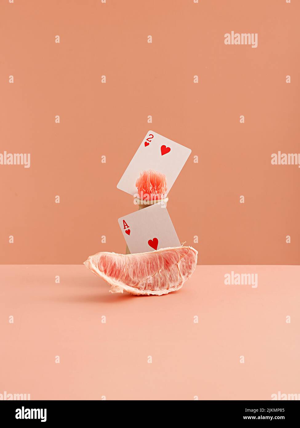 Une tranche de pamplemousse et des cartes de cœur sur fond rose clair Banque D'Images