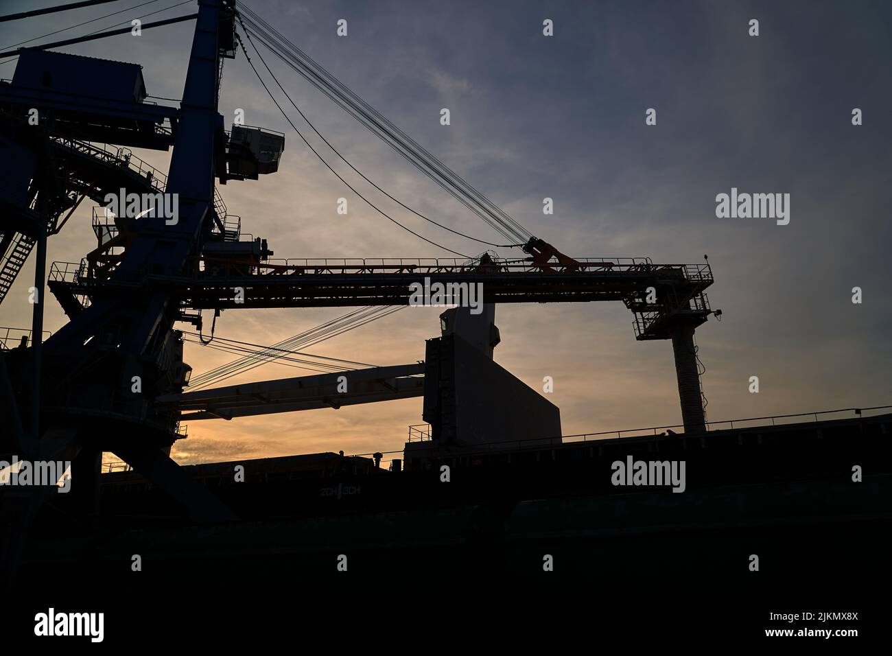 silhouette de grues portuaires sur fond de coucher de soleil. Banque D'Images