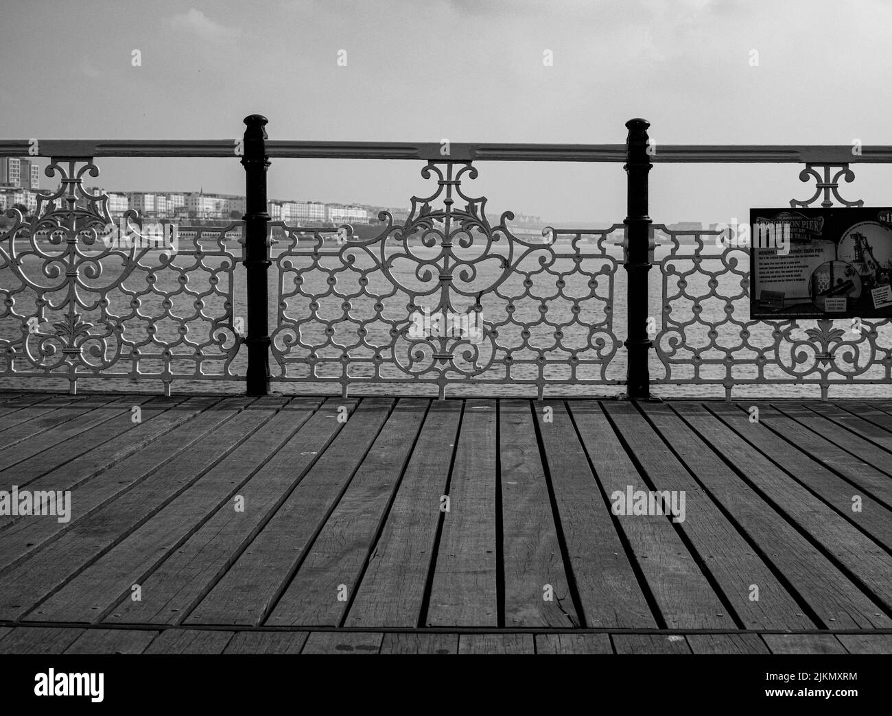 A grayscale Symmetrical shot of a of wooden floor and metal fence on Brighton Pier in United Kingdom Banque D'Images