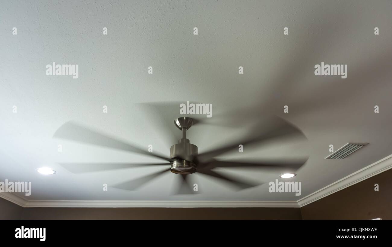 Un ventilateur intérieur en mouvement et flou à l'intérieur d'une nouvelle maison de construction avec un plafond blanc Banque D'Images