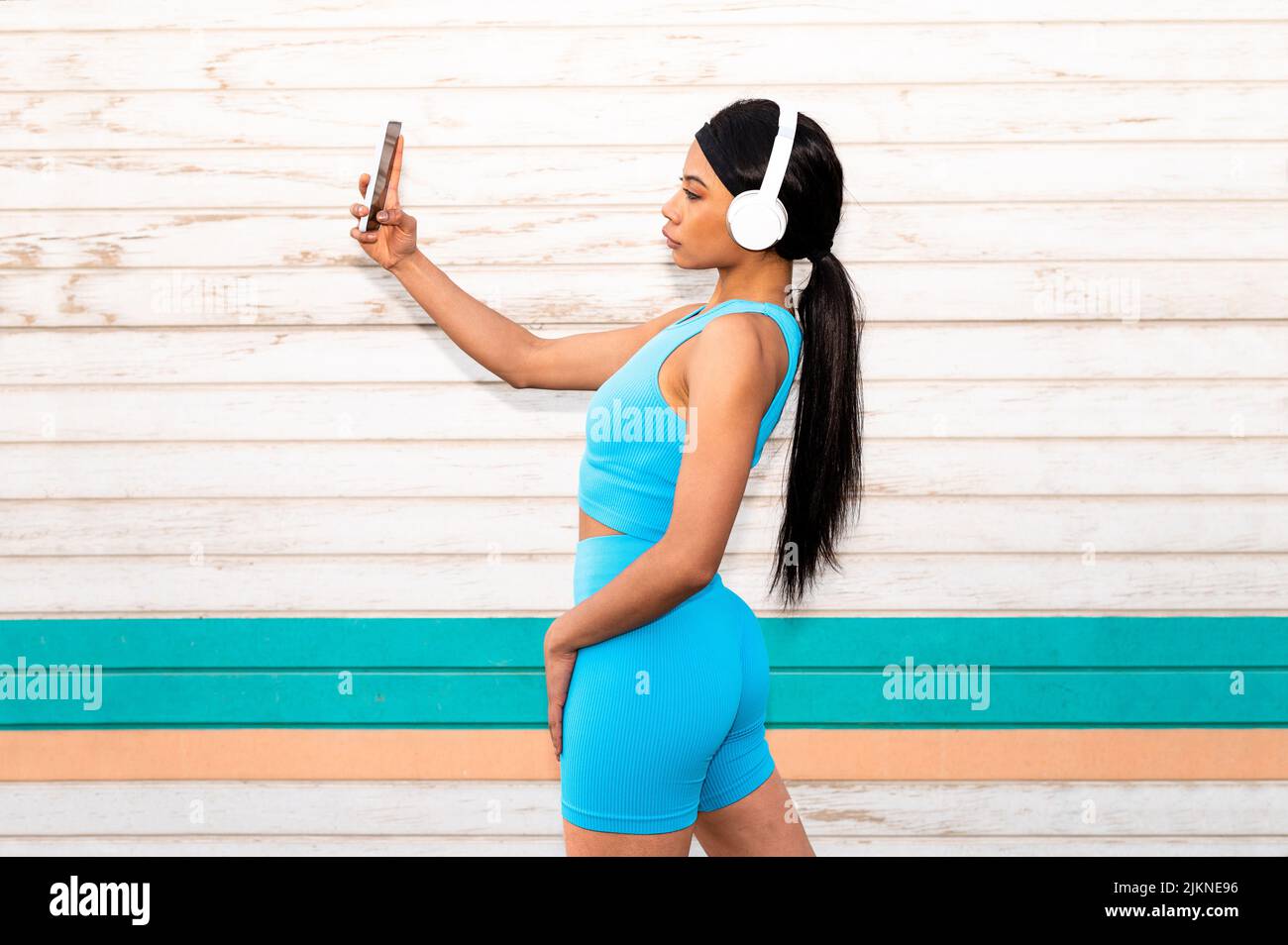 Une jolie femme afro-américaine portant des vêtements de sport et des écouteurs qui prend une photo avec son appareil photo Banque D'Images