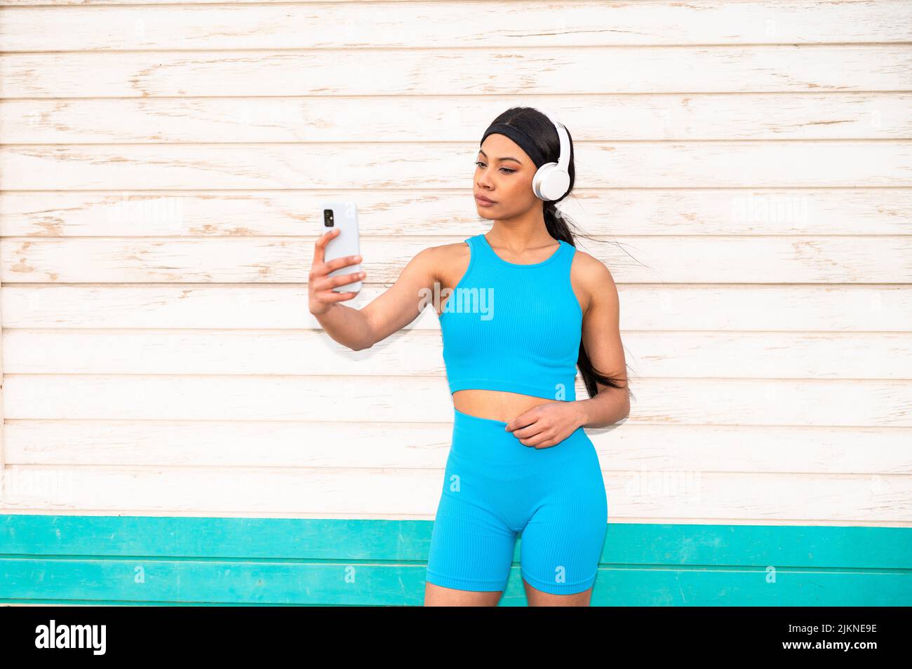 Une jolie femme afro-américaine portant des vêtements de sport et des écouteurs qui prend une photo avec son appareil photo Banque D'Images