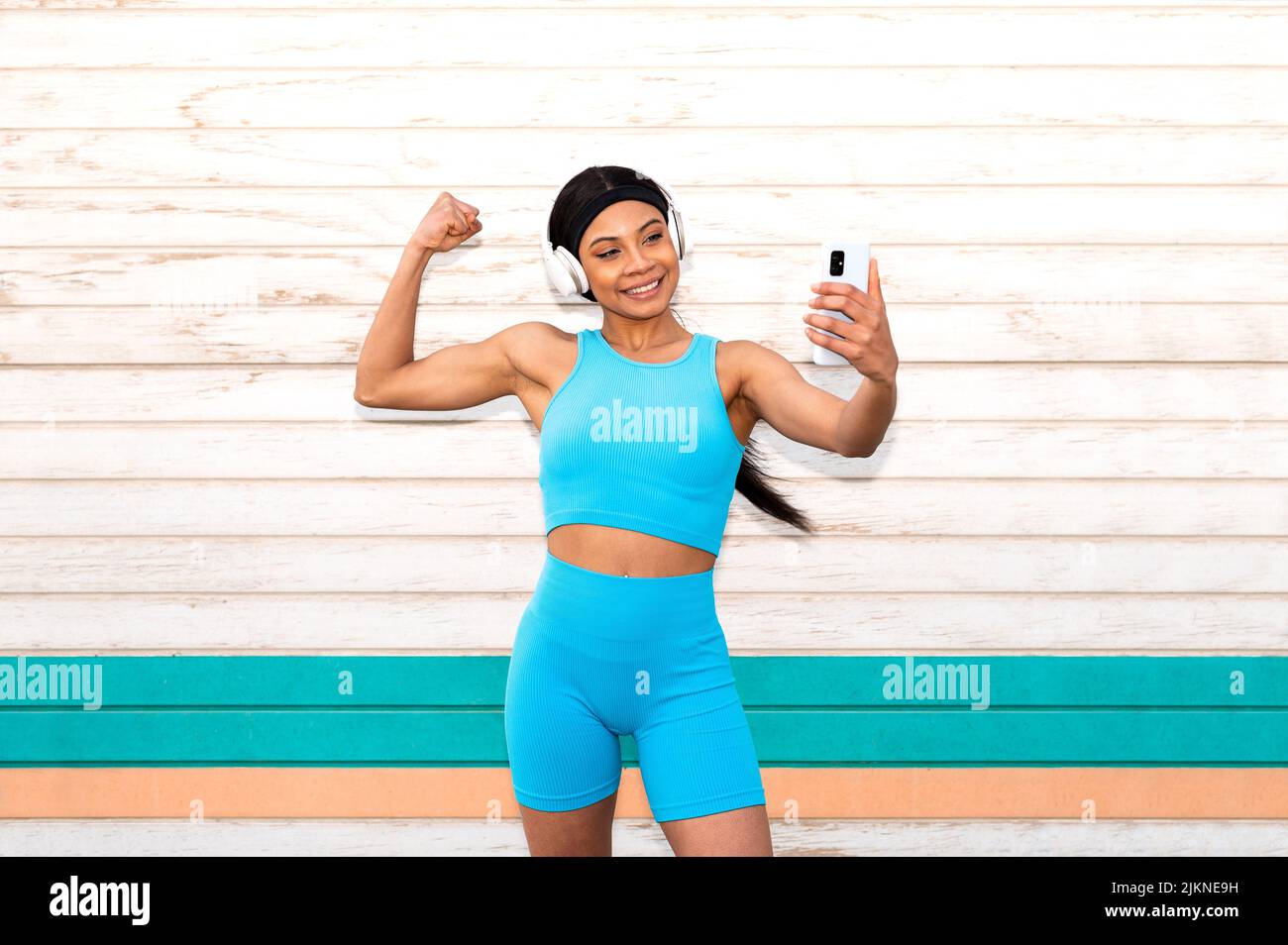 Une jolie femme afro-américaine portant des vêtements de sport et des écouteurs qui prend une photo avec son appareil photo Banque D'Images