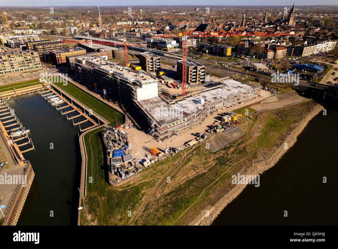 Boulevard view of luxury apartment complex construction at riverbank of river IJssel between train tracks and recreational port. Banque D'Images