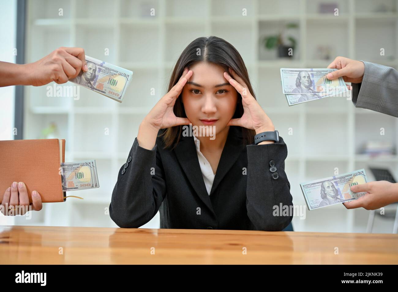 Une jeune femme d'affaires ou une employée asiatique stressée est assise au bureau et les clients tentent de lui offrir un pot-de-vin. Concept anti-corruption Banque D'Images
