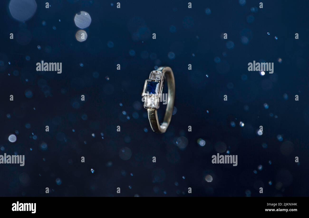 Gros plan d'un anneau avec une pierre bleue sur un arrière-plan abstrait Banque D'Images