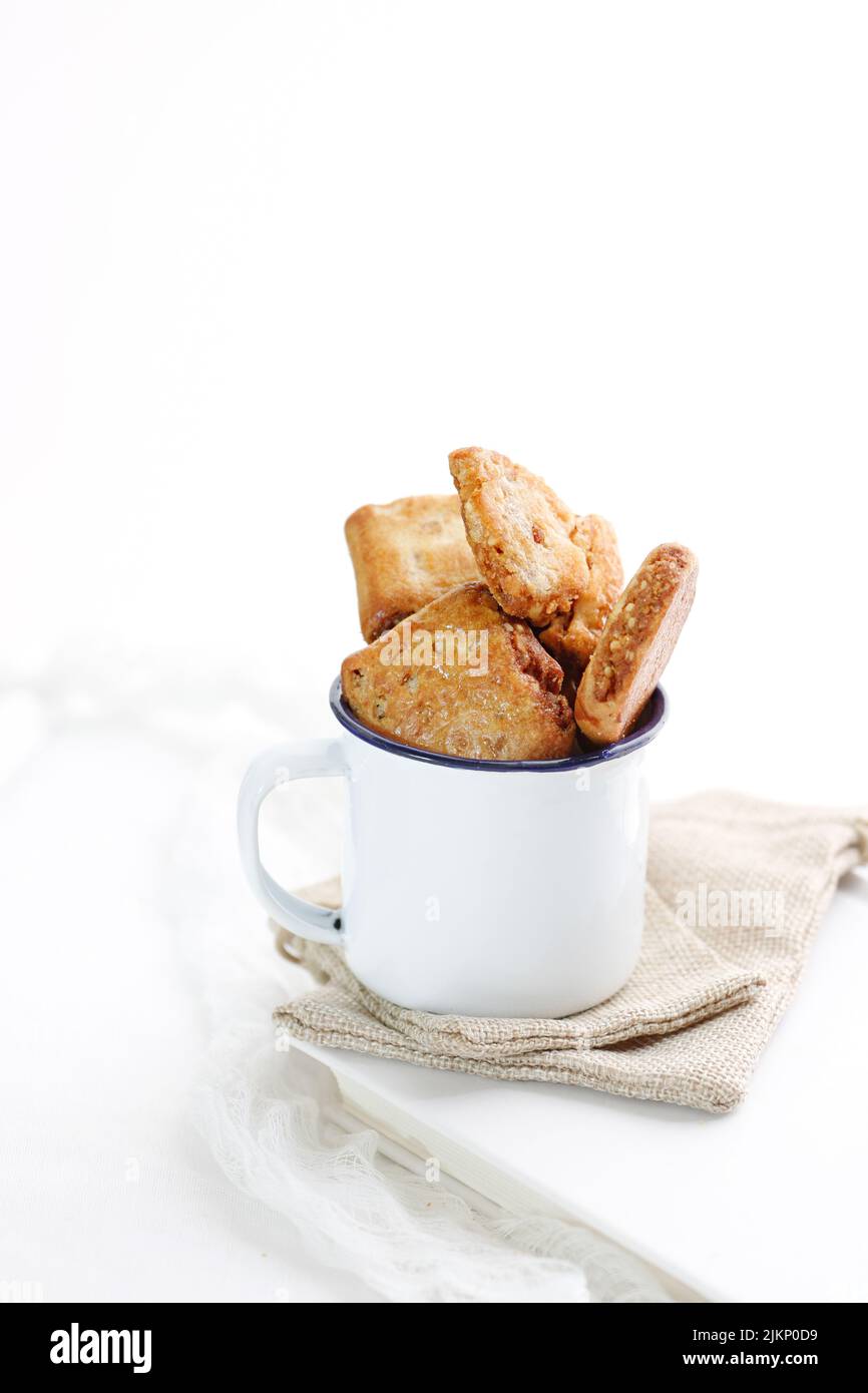 Un cliché vertical de biscuits dans une tasse en métal sur fond blanc Banque D'Images