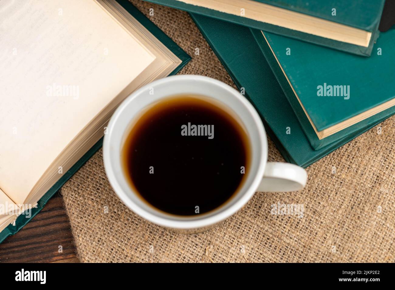Une tasse de thé fort sur une soucoupe et une pile de livres sur la table. Banque D'Images