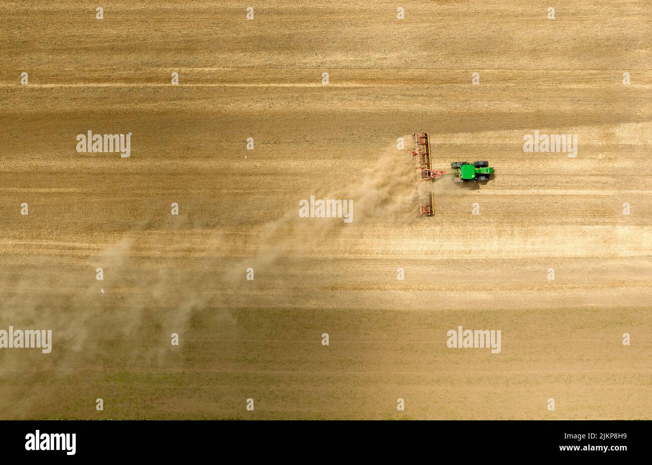 Un agriculteur de son tracteur John Deere, avec des chenilles caterpillar, fait monter la poussière en travaillant sur son champ près de Wisbech, Cambridgeshire. Banque D'Images
