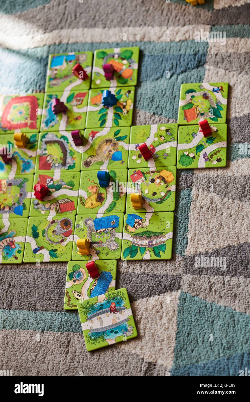 A vertical of the Carcassonne Junior game with cards and colorful wooden figurines on a carpet Banque D'Images