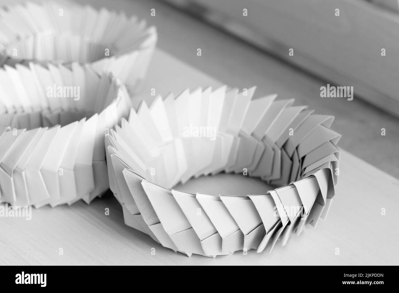 Anneaux d'origami. Objets paramétriques blancs abstraits composés de feuilles de papier liées Banque D'Images