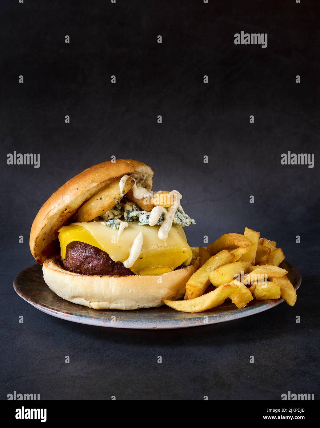 Une photo en studio d'un hamburger frais avec des frites sur fond sombre Banque D'Images