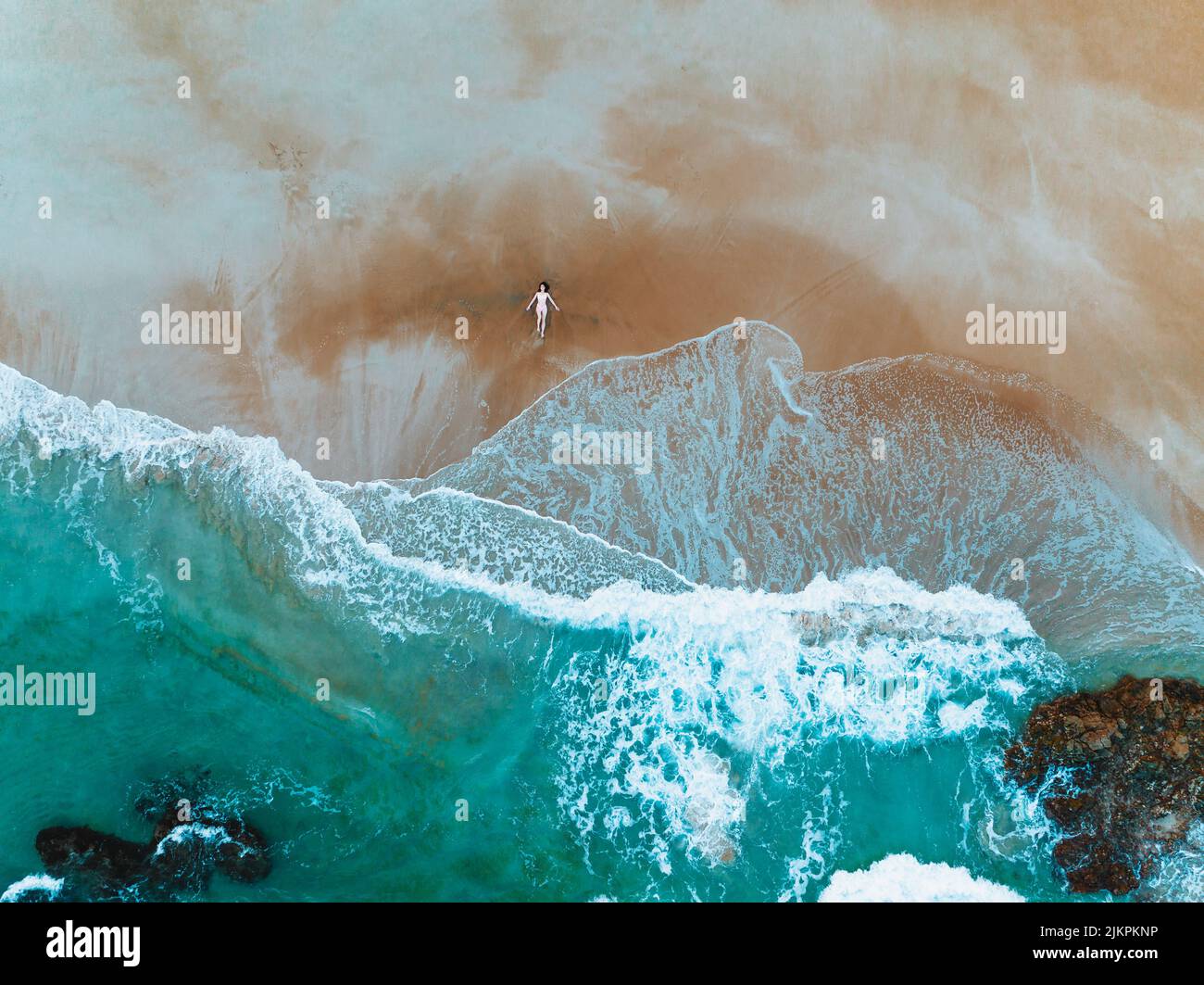 Une vue aérienne des vagues qui éclabousse sur une rive sablonneuse Banque D'Images