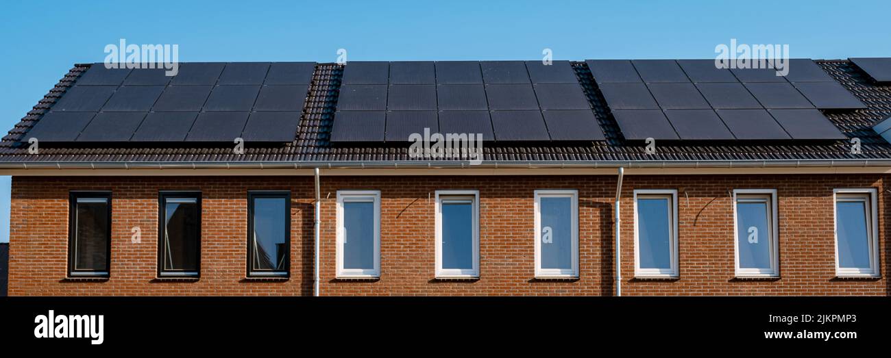 Maisons nouvellement construites avec des panneaux solaires attachés sur le toit contre un ciel ensoleillé gros plan d'un nouveau bâtiment avec des panneaux solaires noirs. Zonnepanelen, Zonne energie, Traduction: Panneau solaire, , énergie solaire. Banque D'Images