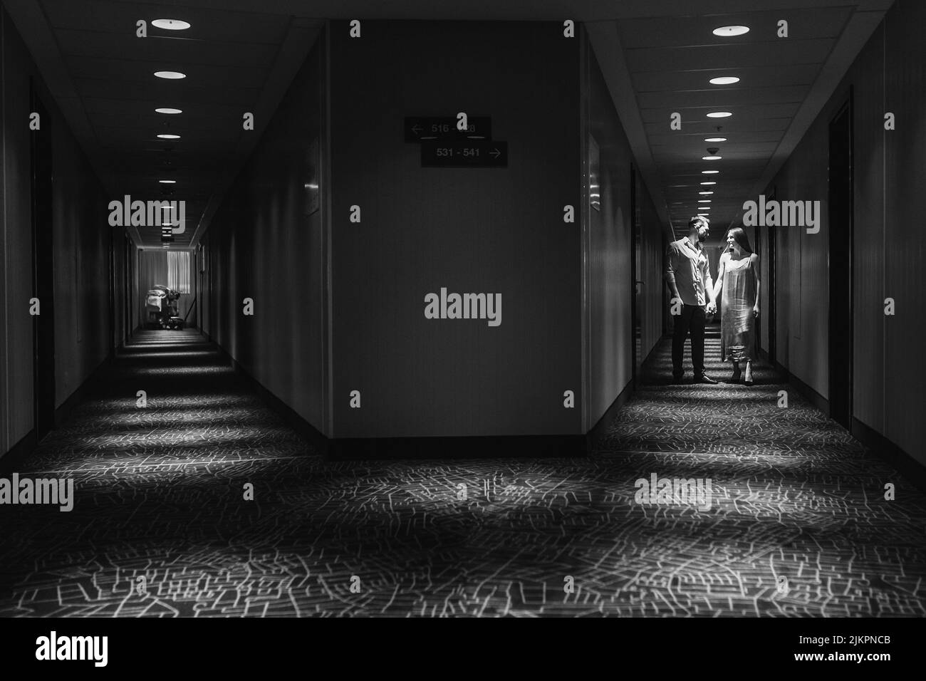 Couple amoureux debout et embrassant dans le couloir de l'hôtel en marchant le long du couloir de l'hôtel Banque D'Images