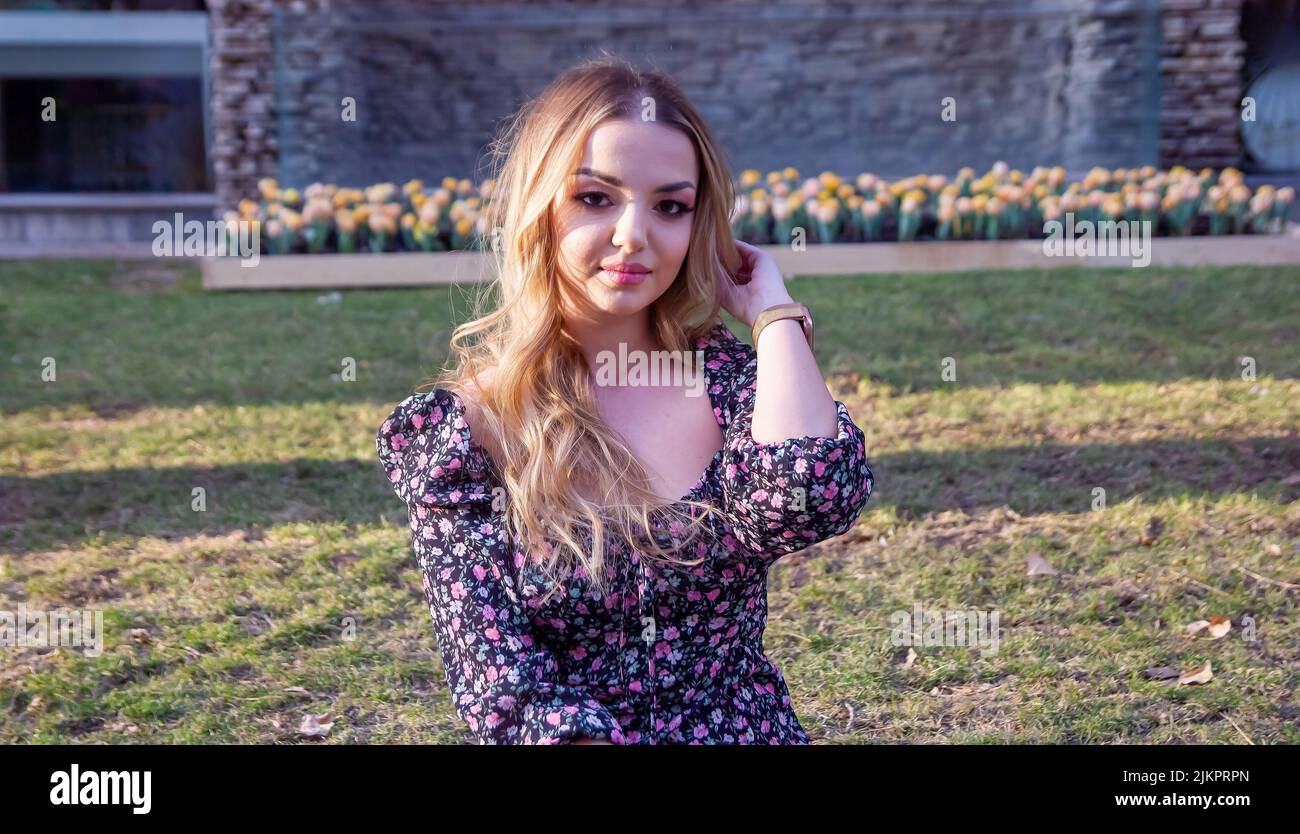 Une belle jeune femme caucasienne portant une robe florale posant à l'extérieur Banque D'Images