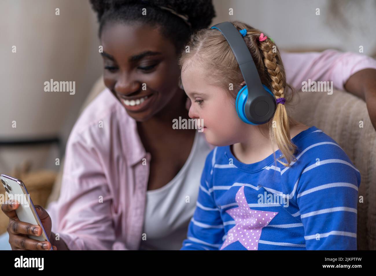 Une fille dans les hédphones assis sur le canapé avec une femme Banque D'Images